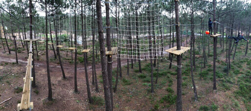 Parque aventura na Ericeira com plataformas de madeira, rede de escalada e tirolesa entre pinheiros